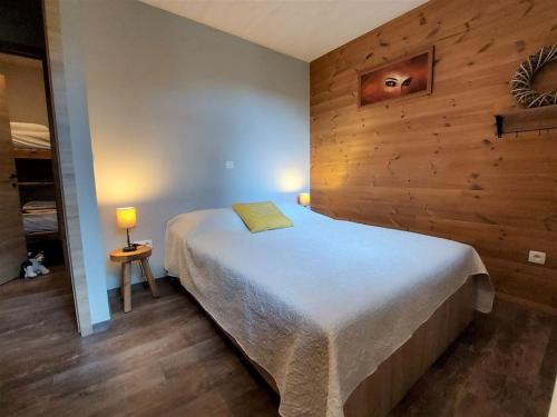 a bedroom with a bed with a wooden wall at Chalet Noisette in Durbuy
