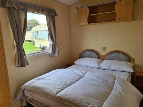 a bed in a room with a window at 8 berth central heated on Coral Beach ABI CB in Ingoldmells