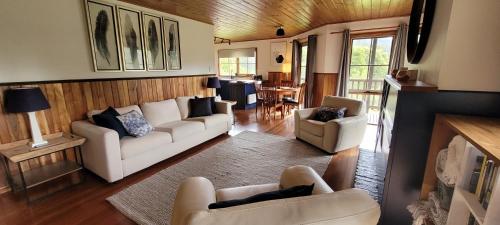 a living room with white couches and a dining room at Tall Trees Eco Retreat in Apollo Bay