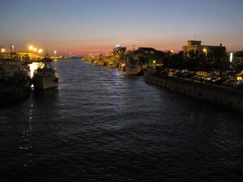 a river with boats docked in a city at night at Fiumicino Inn Airport in Fiumicino