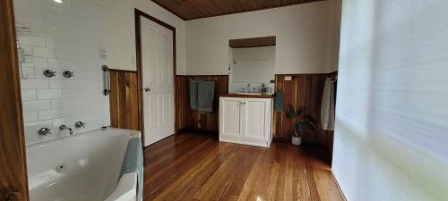 a large bathroom with a tub and a wooden floor at Tall Trees Eco Retreat - Blackwood Cottage in Apollo Bay