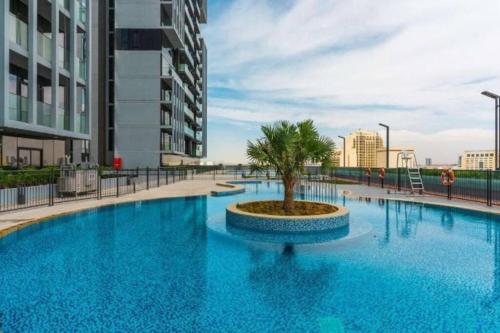 a large blue pool with a palm tree in the middle at High floor 1BR vacation home with terrace in Dubai