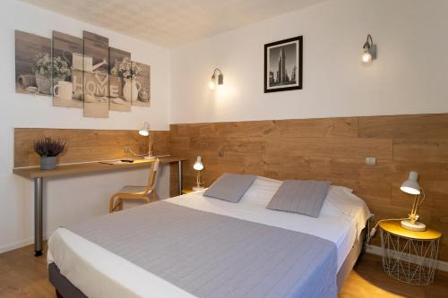Schlafzimmer mit einem Bett und einem Schreibtisch mit Lampen in der Unterkunft Hôtel du Midi in Domène