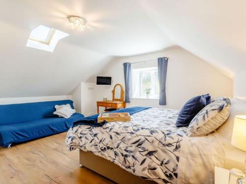 a bedroom with a bed and a blue couch at Pea Cottage in Ilchester