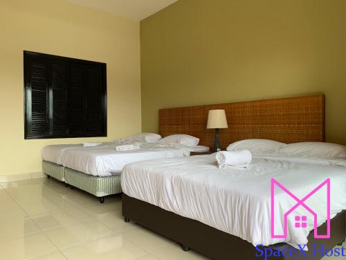 two beds in a hotel room with white sheets at Gold Coast Morib Resort in Banting