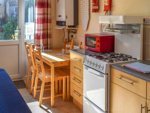 a kitchen with a stove and a table with a microwave at 16 Beech Cottage-uk38936 in Porthcurno
