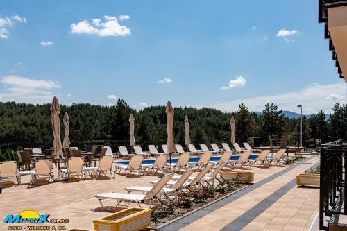a row of lounge chairs and umbrellas on a patio at Monix Palace Zlatibor in Zlatibor