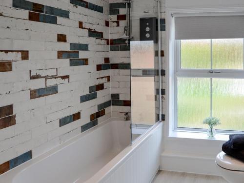 a bathroom with a tub and a window at Sea La Vie in Sheringham