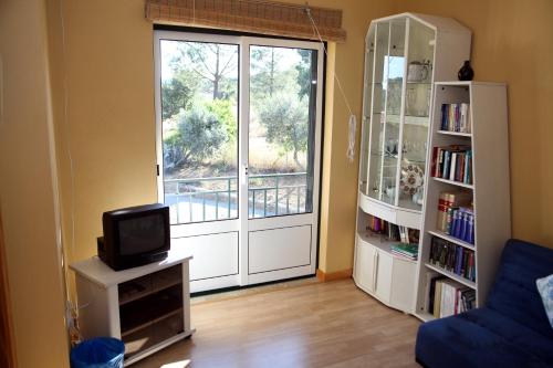 a living room with a door with a tv and a book shelf at Quinta do Mineiro-Serra da Estrela in Matança