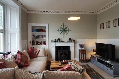 a living room with a couch and a fireplace at Superb Loch Side Apartment with Sea & Sunset Views in Helensburgh