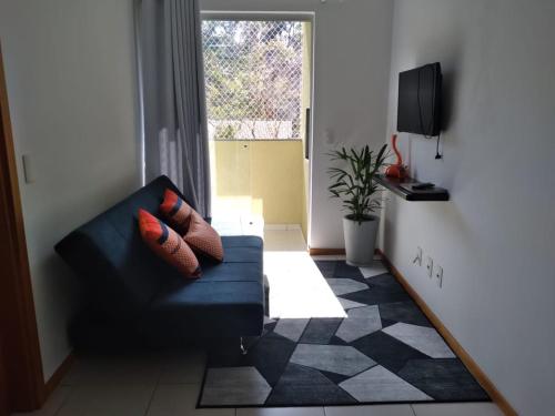 uma sala de estar com um sofá azul e uma janela em Apartamento ao lado da Vila Germânica em Blumenau
