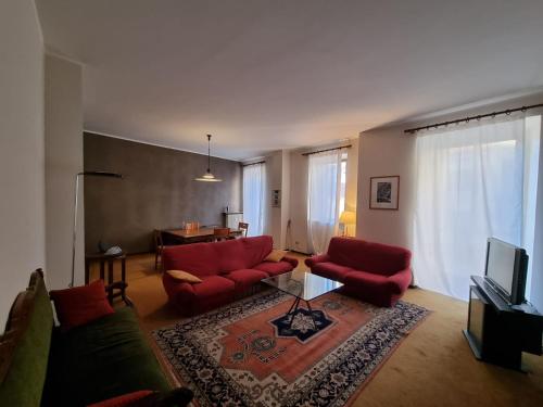 a living room with red couches and a television at Santa Marta Apartment in Biella