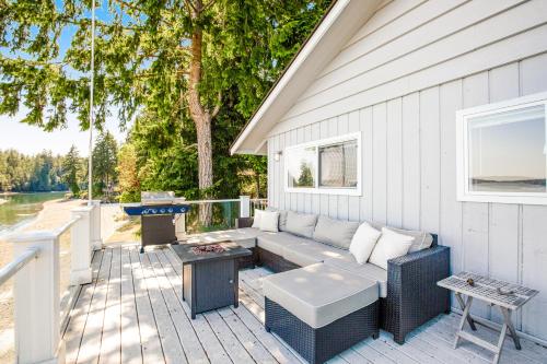 a patio with a couch and a table on a deck at Sound of Sight in Allyn