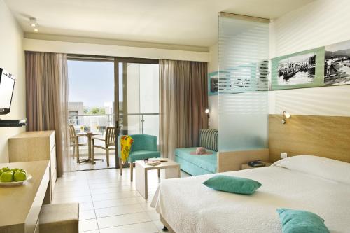 プリノスにあるALEA Hotel & Suitesのベッドとリビングルームが備わるホテルルームです。