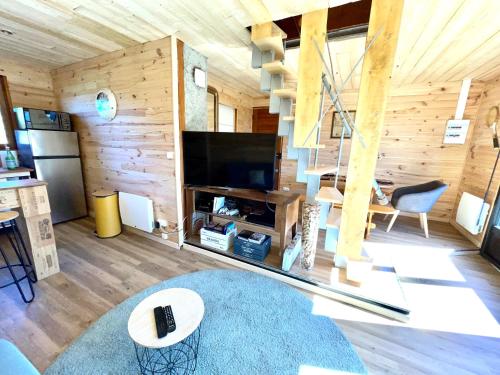 a living room with wooden walls and a large television at La cabane au pied des pistes in Chastreix