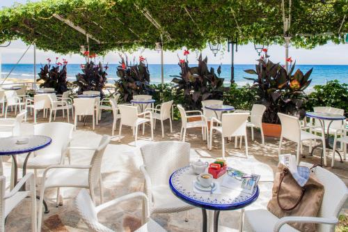 a restaurant on the beach with tables and chairs at Hotel Beau Sejour in Alassio
