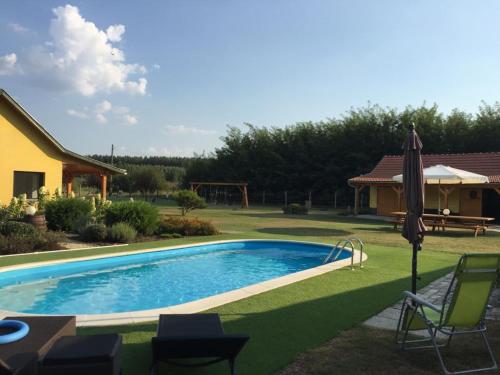 uma piscina num quintal com cadeiras e um guarda-sol em Sunshine Tanya em Nagykőrös