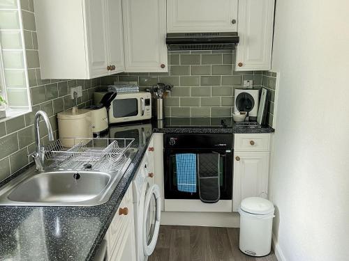 a small kitchen with a sink and a microwave at The Steps in Pentewan