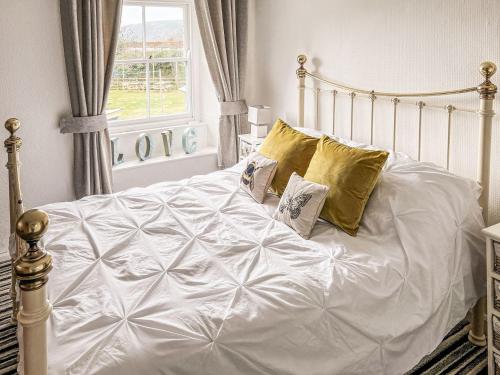 a bed with white sheets and pillows in a bedroom at The Steps in Pentewan