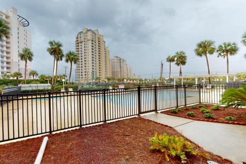 a black fence with palm trees and a body of water at Grand Caribbean West 0107 in Perdido Key