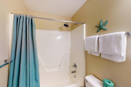 a bathroom with a shower and a blue shower curtain at Grand Caribbean West 0107 in Perdido Key