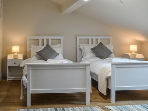 a bedroom with two white beds and two tables at The Barn Pencoed Farm in Aberdare