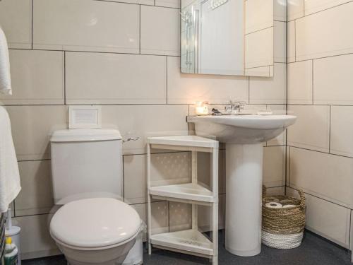 a white bathroom with a toilet and a sink at The Barn Pencoed Farm in Aberdare