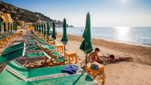 a group of lawn chairs and umbrellas on a beach at Hotel Beau Sejour in Alassio