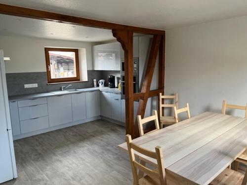 une cuisine avec une table en bois et une table et des chaises dans l'établissement Maison Alsacienne, à Baldenheim