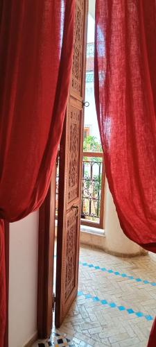 an open door with red curtains and a window at Riad Asrari in Marrakech