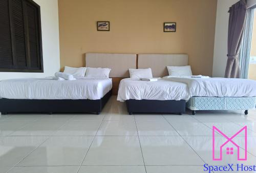 two beds in a hotel room with white sheets at Gold Coast Morib Resort in Banting