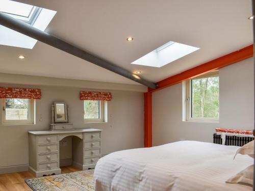 a bedroom with a bed and a desk and windows at Larch Cottage - Uk36198 in Fordingbridge