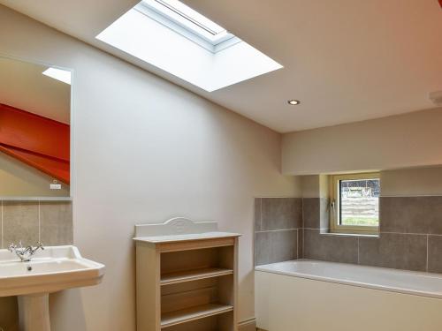 a bathroom with a sink and a bath tub and a skylight at Larch Cottage - Uk36198 in Fordingbridge