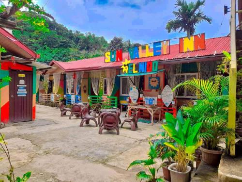 a group of colorful buildings with tables and chairs at Sun Valley Hostel in El Nido