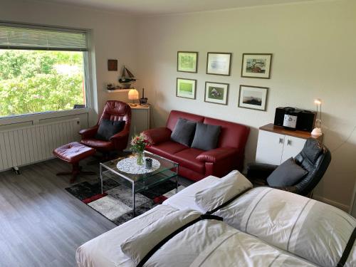 ein Wohnzimmer mit einem roten Sofa und Stühlen in der Unterkunft Ferienwohnung "Palstek" im Haus Düwelswarft in Sankt Peter-Ording