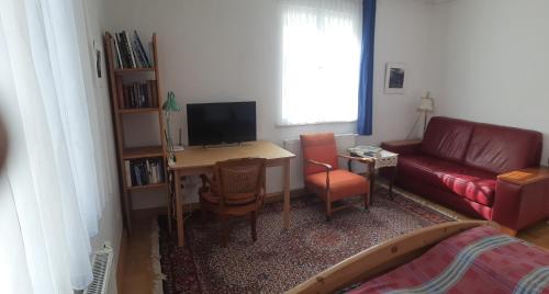 a living room with a couch and a desk with a television at Paulus Gästehaus Top 2 in Salzburg