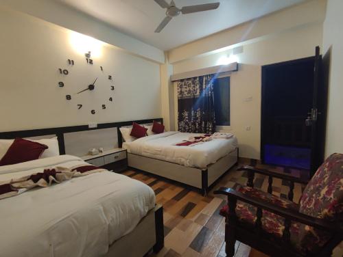 a hotel room with two beds and a clock on the wall at Hotel Kajiinn in Pokhara