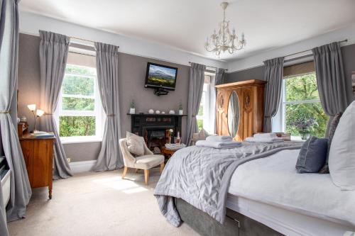 a bedroom with a large bed and a fireplace at Afon Rhaiadr Country House in Dolgellau