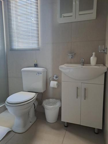 a white bathroom with a toilet and a sink at Sterrenhemel Guest Farm in Upington