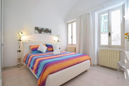 een slaapkamer met een bed met een kleurrijk gestreepte deken bij Casa Titen in Ventimiglia