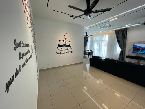 a living room with a couch and a sign on the wall at 家好月圆 Sweet Home in Kampong Seri Gading