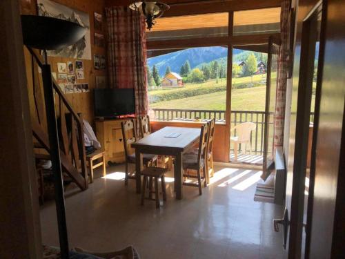 ein Esszimmer mit einem Tisch und einem großen Fenster in der Unterkunft Appartement Au Pied Des Pistes in Puy-Saint-Vincent