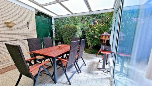 a patio with a wooden table and chairs on a patio at Ferienhaus "Auberge Jolie" in Aachen