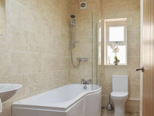 uma casa de banho com uma banheira, um WC e um lavatório. em Derwent Apartment em Glossop