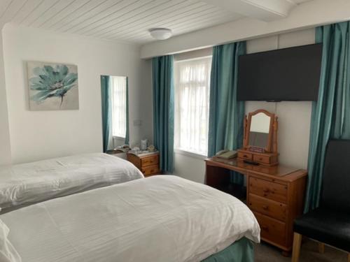 a bedroom with a bed and a dresser and a mirror at Rosemundy House Hotel in St. Agnes