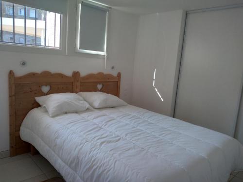 - une chambre dotée d'un grand lit avec des draps blancs et une fenêtre dans l'établissement La Bernaudine bis, à Annonay