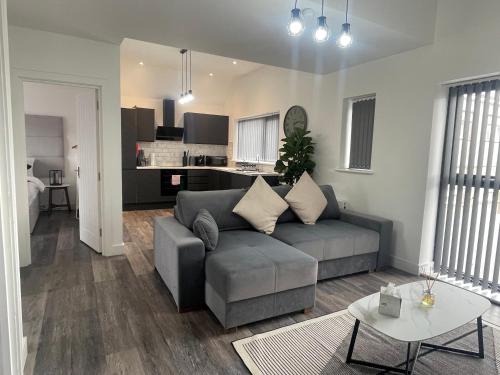 a living room with a gray couch and a kitchen at Sapphire Premier Apartments w/Secure Parking in Cardiff