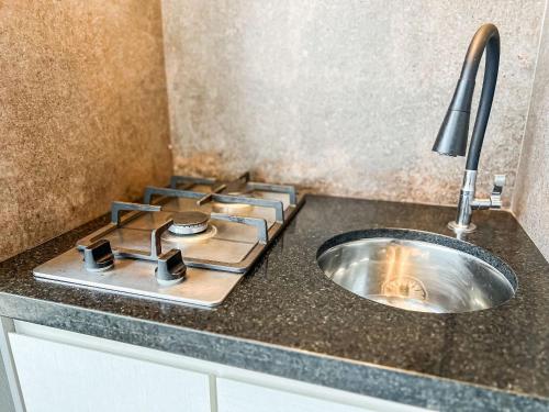 a kitchen counter with a stove and a sink at Condomínio Residencial Unique Residence - São José do Rio Preto in Sao Jose do Rio Preto