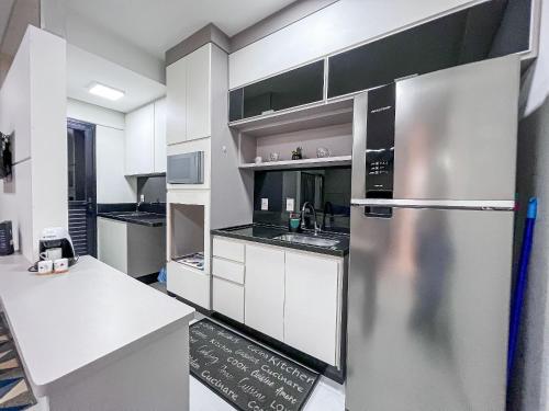 a kitchen with a stainless steel refrigerator and white cabinets at Condomínio Residencial Unique Residence - São José do Rio Preto in Sao Jose do Rio Preto