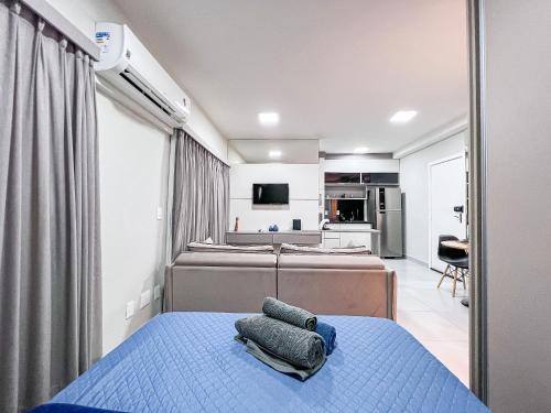 a bedroom with a blue bed and a kitchen at Condomínio Residencial Unique Residence - São José do Rio Preto in Sao Jose do Rio Preto